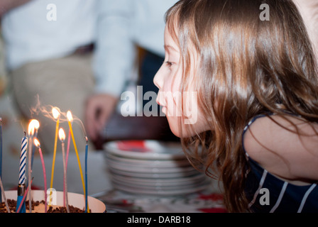 Mädchen bläst Kerzen draußen auf einem Geburtstag Kuchen Stockfoto