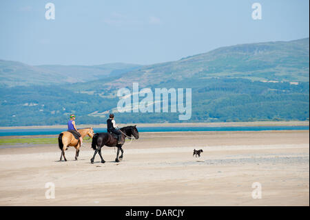 Dovey Mündung/Borth, Ceredigion, Wales, UK. 17. Juli 2013. Zwei Frauen fahren ihre Pferde auf dem Sand. Eine Ausdehnung der harten Sand-die Wohnung bietet einen großen Parkplatz für Autos £ 1 pro Auto und Tag - in der Mündung des Dovey (Dyfi auf Walisisch), ist Teil eines großen Gebietes der Küstengewässer von der Landschaft Rat für Wales verfochten und zusammen mit den umliegenden Dünen bietet eine herrliche Gegend für Menschen zu entkommen, die Hitzewelle, die Großbritannien seit fast zwei Wochen glühend gewesen hat. Einladende kühle Meeresbrise bläst von der irischen See. Bildnachweis: Graham M. Lawrence/Alamy Live-Nachrichten. Stockfoto