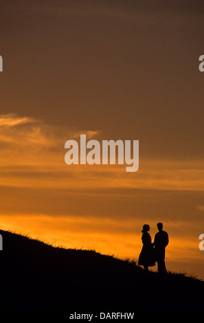 Silhouette Frau und Mann bei Sonnenuntergang stehen auf Klippe Sonnenuntergang und reden Stockfoto