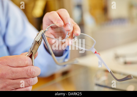 Hand der Optiker Befestigung Gläser mit einer Zange biegen Stockfoto