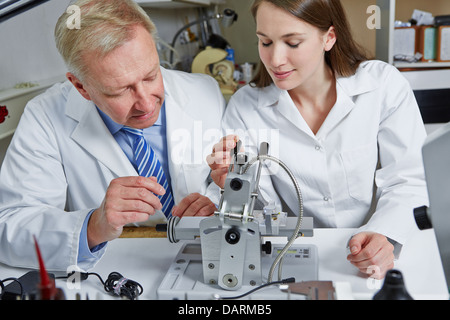 Junge Frau als Lehrling an Optiker-Workshop zur Bohrmaschine Stockfoto