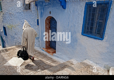 Mann trägt Djellaba und zu Fuß durch die Straßen der blauen Medina. Chefchaouen, Rif-Region, Marokko Stockfoto
