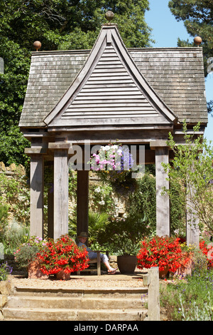 Junge tragen Sonnenhut saß im Pavillon an Abbotsbury subtropischen Gärten, Abbotsbury, Dorset, England UK an einem heißen sonnigen Tag im Juli Stockfoto