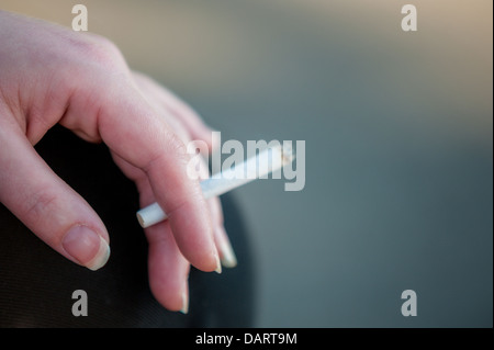 Ein close-up selektiven Fokus einer kaukasischen Frau Hand mit einer brennenden Zigarette. Stockfoto