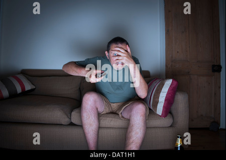 Manndeckung Gesicht vor dem Fernseher Stockfoto