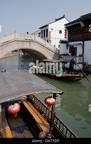 China, Stadtrand von Shanghai. Wasser Dorf Zhujiajiao. Traditionellen Holzboot in schmalen Fluss Kanal, alte Steinbrücke. Stockfoto