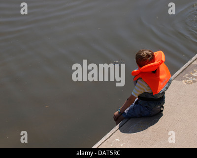 Kleiner Junge saß auf dem Kai tragen einer Rettungsweste, Kingsbridge, Devon, UK 2013 Stockfoto