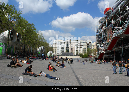 Touristen, die entspannend sitzen / Verlegung vor dem Museum für moderne Kunst (Centre George Pompidou) in Paris, Frankreich Stockfoto