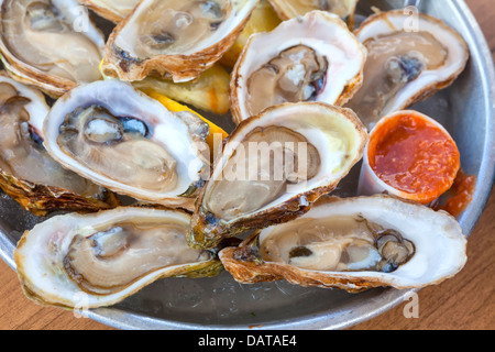 Eine Platte mit frischen rohen Austern auf Eis in einem Straßencafé. Stockfoto