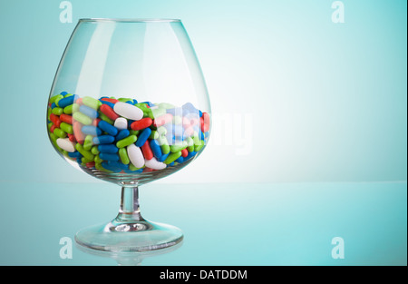 Rote und weiße Medikament Pillen in der Whiskyglas als ein Konzept von zu viel trinken, um Medizin benötigen Stockfoto