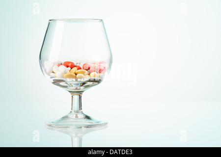 Rote und weiße Medikament Pillen in der Whiskyglas als Konzept des Trinkens Missbrauch Stockfoto