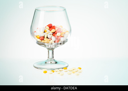 Trinken Problem Allegorie von Whisky Klasse voller Medikamente und Pillen auf dem Tisch verstreut dargestellt Stockfoto
