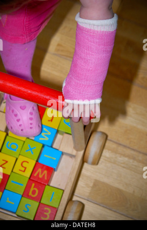 Junge Mädchen mit einem rosa Guss-Verband auf einem gebrochenen Arm. Buntes Bild, Textfreiraum, Kleinkind, 2 Jahre altes Kind, Mädchen. Stockfoto