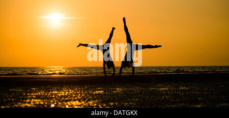 Ynyslas Strand, Ceredigion, Wales, UK, ist Donnerstag, 18. Juli 2013 am Ende von dem, was einer der heißesten Tage des Jahres, zwei Frauen führen akrobatische Übungen am Ynyslas Beach, nördlich von Aberystwyth, Ceredigion, Wales UK.  Der Zauber der hohe Druck, mit kontinuierlichen ununterbrochenen Sonnenschein und Temperaturen bis 29 Grad Celsius ist die längste Periode des guten Sommerwetter im Vereinigten Königreich seit 2006. Warnungen ausgestellt wurden in weiten Teilen des Landes über die Gefahren von hohen Temperaturen an den jungen, Kranken und älteren Bildnachweis: Keith Morris/Alamy Live-Nachrichten Stockfoto