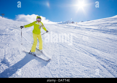 Glückliche junge Frau Ski in den Bergen mit ihren Händen aufgehoben mit dem Ausdruck ihrer Freude Stockfoto