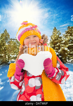 Wenig glückliches Mädchen halten Herz aus Schnee in gelbes Tuch und hellen Hut gemacht Stockfoto