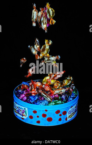 Pralinen in der Dose vor einem schwarzen Hintergrund gelöscht wird. Stockfoto