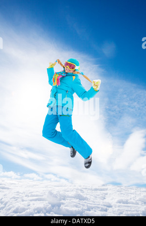 Fröhliches blondes Mädchen mit langen Zöpfen springen an kalten Wintertag im Schnee Stockfoto