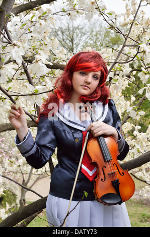 Teenager-Mädchen mit der Geige im blühenden Garten Stockfoto