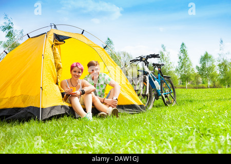 Paar im Zelt sitzen und trinken Tee mit Bikes stehen in der Nähe von Stockfoto