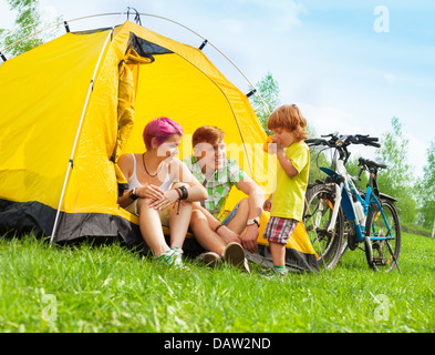 Junges Paar sitzt im Zelt mit kleinen Jungen Teetrinken mit Bikes Stand in der Nähe Stockfoto