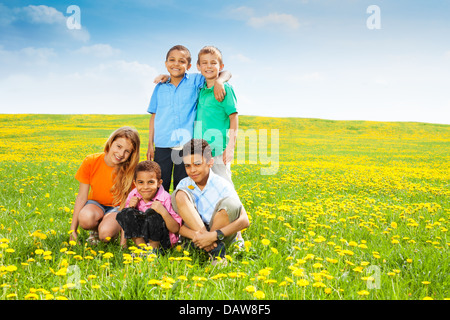 Fünf glückliche Vielfalt aussehende Kinder, jungen und Mädchen im Feld sauber Löwenzahn Stockfoto