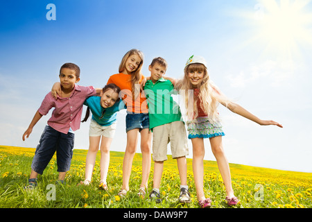 Fünf glückliche Kinder, jungen und Mädchen umarmt zusammen stehen im Feld gelbe Blume Stockfoto