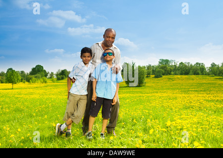 Glückliche schwarz Vater mit seinen Söhnen stehen auf dem Rasen im Park am sonnigen Tag Stockfoto