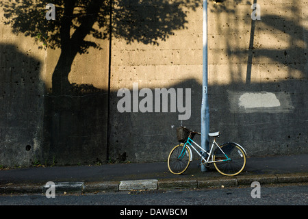 Fahrrad gegen Lampost, Schatten eines Baumes geparkt Stockfoto