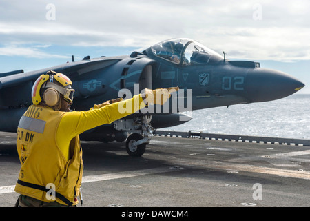Ein US-Marine Aviation Bootsmännern Mate signalisiert dem Piloten eine AV-8 b Harrier-Kampfflugzeuge, dass er für den Start aus dem Flugdeck der amphibischen Angriff Schiff USS Bonhomme Richard 16. Juli 2013 in der Coral Sea deaktiviert ist. Stockfoto
