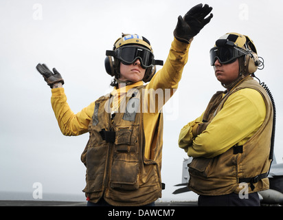 Ein uns Marine Aviation Bootsmann der Mate erhält eine Ausbildung auf Handzeichen Flugzeuge auf dem Flugdeck des Flugzeugträgers USS Nimitz 15. Juli 2013 in den Golf von Oman. Stockfoto