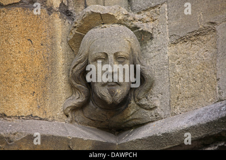 Einen sehr alten geschnitzten Kopf in einem Sandsteinblock auf ein Torhaus in der Stadt, die Anzeichen des Alters und Verschmutzung. Stockfoto