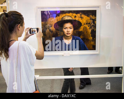 19. Juli 2013 - Bangkok, Thailand - nimmt Thai-Frau ein Bild von Steve McCurry Fotos hängen in einer Show in CentralWorld in Bangkok. Die US-Botschaft in Bangkok sponserte die Fotoausstellung, die feiert 180 Jahre US-thailändische diplomatische Beziehungen. Es gibt 180 Fotos hängen in der Show, 90 von amerikanischen Fotografen in Thailand und 90 von Thai Fotografen in den Vereinigten Staaten. Die Show, die 19 Juli eröffnete hängt im CentralWorld, ein großes Einkaufszentrum in Bangkok, und tourt Thailand, wenn es seine Bangkok laufen am 21. Juli abgeschlossen. (Bild Kredit: Jack Kurtz/ZUMAPRESS.com ©) Stockfoto