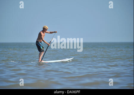 BARRY ISLAND, VEREINIGTES KÖNIGREICH. 19. Juli 2013. Die britische Hitzewelle weiter und die Menschen strömen zu den Stränden in Süd-Wales. Ein Mann Paddel durch das Wasser stehend auf einem Surfbrett. Foto Credit: Polly Thomas / Alamy Live News Stockfoto