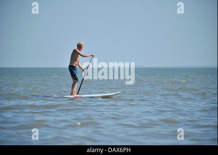 BARRY ISLAND, VEREINIGTES KÖNIGREICH. 19. Juli 2013. Die britische Hitzewelle weiter und die Menschen strömen zu den Stränden in Süd-Wales. Ein Mann Paddel durch das Wasser stehend auf einem Surfbrett. Foto Credit: Polly Thomas / Alamy Live News Stockfoto