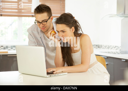 Junges Paar in einer Küche mit einem Laptop zusammen. Stockfoto