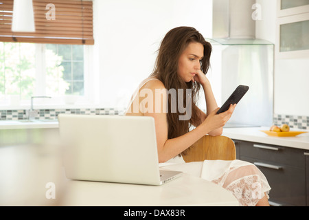 Ziemlich dunkelhaarige junge Frau in einer Küche, eine e-Reader-Buch zu lesen. Stockfoto