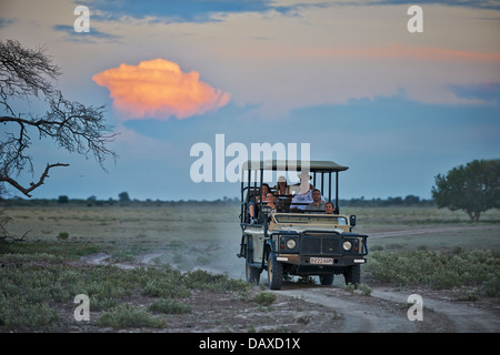 4 x 4 Safari Auto mit Touristen und Reiseleiter während des Sonnenuntergangs in Central Kalahari Game Reserve in Botswana, Afrika Stockfoto