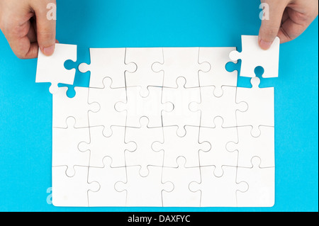 Hand halten Puzzleteile und Einfügen in die Gruppe des Weißbuchs Puzzles Stockfoto