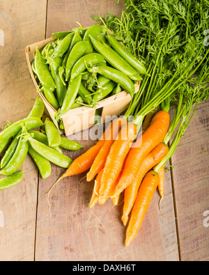 Frisch geerntete grüne Erbsen und Karotten Stockfoto