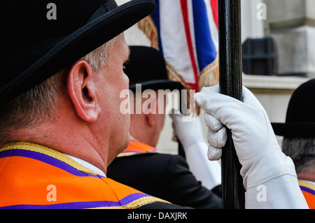 Ein Orangeman trägt eine Orange Schärpe und Leder Handschuh hält eine Fahnenstange Stockfoto