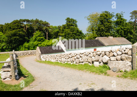 Trockenmauern führen hinunter zu einem weiß getünchten irischen Bauernhaus Stockfoto