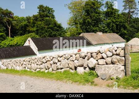 Trockenmauern führen hinunter zu einem weiß getünchten irischen Bauernhaus Stockfoto