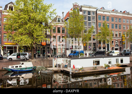 Hausboot und Wohnblocks auf Geldersekade Kanal historischen Hafen in Amsterdam, Niederlande, Nord-Holland. Stockfoto