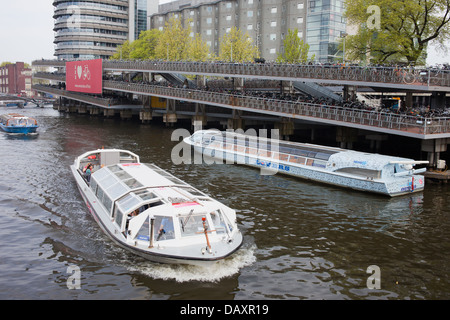 Boote auf Touren und große mehrstufige Fahrrad-Parken in Amsterdam, Niederlande, neben dem Hauptbahnhof. Stockfoto