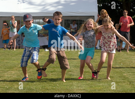 Jugendliche, die Teilnahme an einem zweibeinigen Rennen auf Worldham Dorffest, Hampshire, UK. Sonntag, 14. Juli 2013. Stockfoto