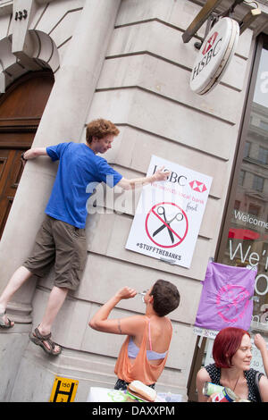 London, UK. 20. Juli 2013. Ein Demonstrant Affixe seinem Banner an der Wand, wie UK Uncut halten Demonstrationen vor zwei London Niederlassungen der HSBC in Protest gegen was sie ist Steuer ausweichen von der Bank sagen als Laufwerk mehr Menschen Vertrauen auf Foodbanks Sozialabbau. Bildnachweis: Paul Davey/Alamy Live-Nachrichten Stockfoto