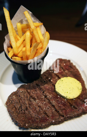 Chips werden mit einem Steak und ein Stückchen Kräuterbutter serviert. Stockfoto