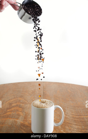 Kaffee Bohnen gießen und wie von Zauberhand verwandelte in flüssiger Kaffee in eine weiße Tasse Stockfoto