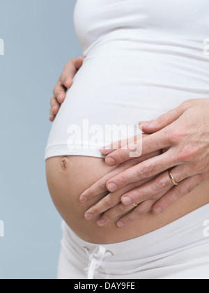 Schwangere Frau mit ihrem Mann die Hände um ihren Bauch. 7. Monat der Schwangerschaft. Stockfoto